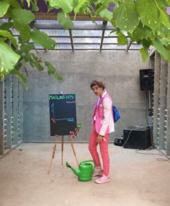 A person standing in a porch next to a watering can
