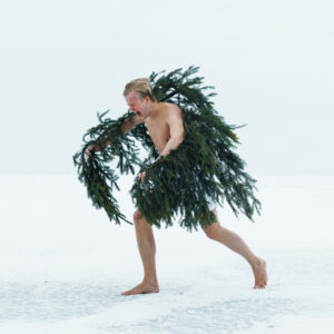 A person snding on snow and wearing pine branches