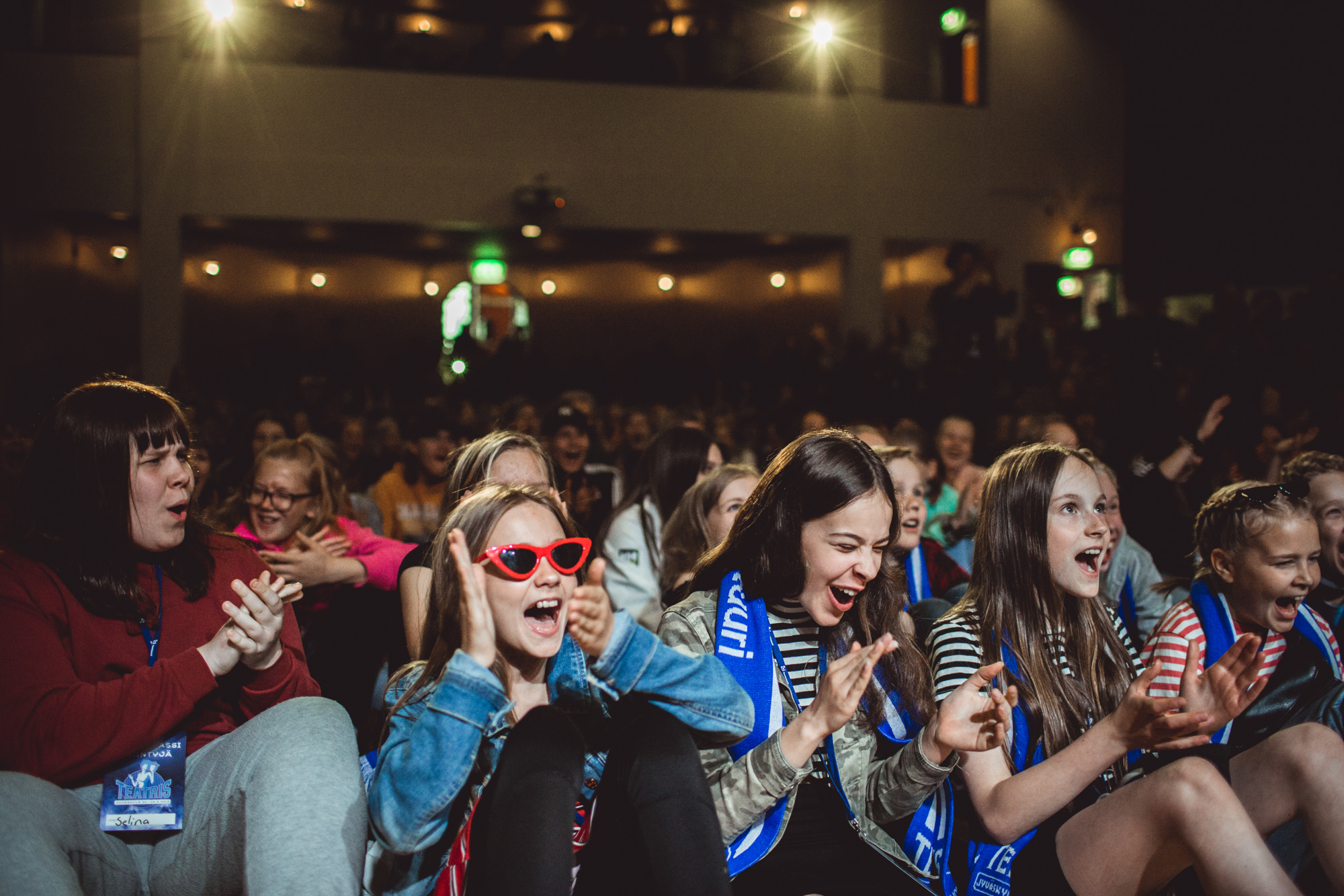 Nuoria innoissan olevia henkilöitä seisoo teatterin katsomossa