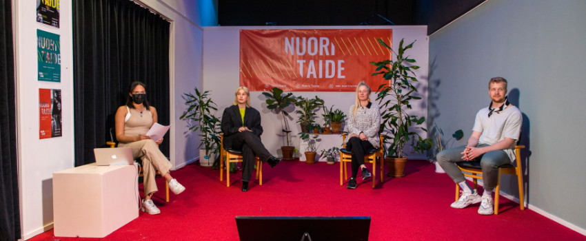 Artikkelikuva nuoritaide.fi Neljä nuorta panelistia vierekkäin, taustalla Nuori Taiteen banderolli sekä viherkasveja. Kuvaaja: Onni Pusa