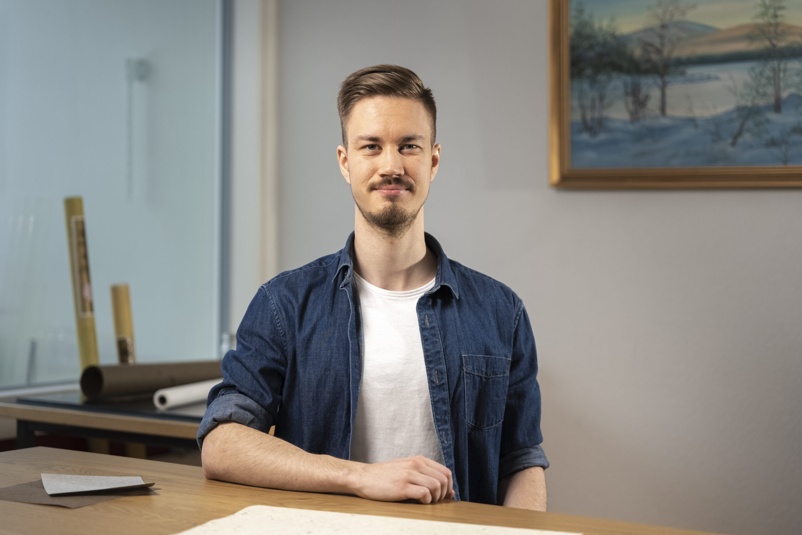 _DSC0563-6 Puolikuva henkilöstä, joka istuu pöydän ääressä. Toinen käsi on pöydän päällä.
