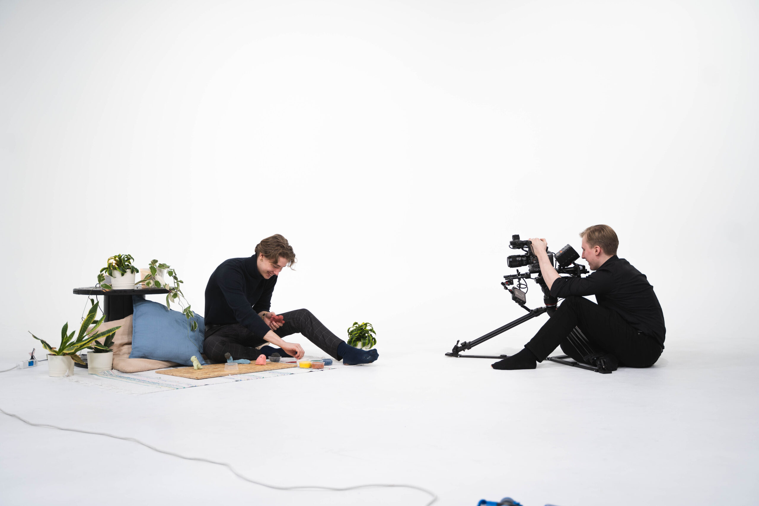 Kaksi henkilö istuu lattialla kahden videokameran kanssa